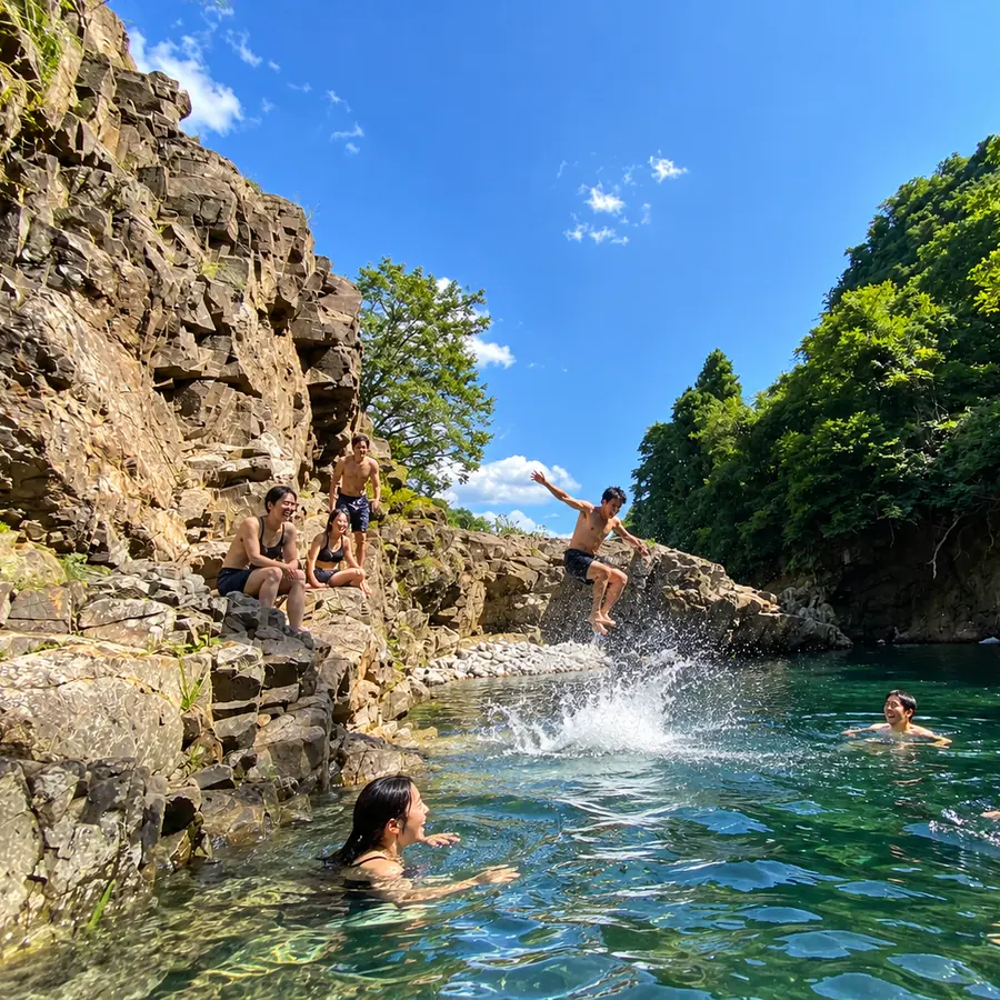 岩場から川の淵へ飛び込む人と、水遊びを楽しむ人たち